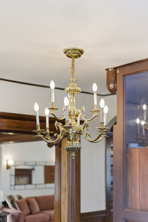 A brass chandelier with candle-like bulbs hangs from the ceiling, adding elegance to a cozy living space.