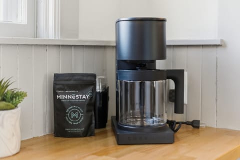 A modern coffee maker next to a bag of Minnesota coffee beans on a wooden countertop.