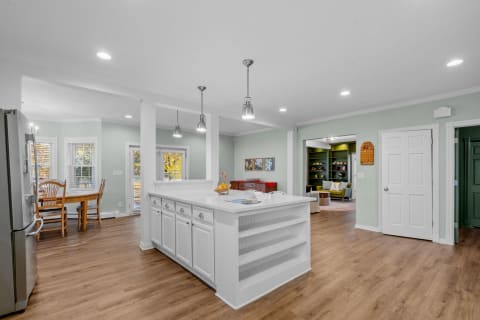 Modern kitchen featuring an island, dining table, and inviting living area in the background.