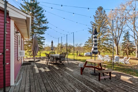 Wooden deck with outdoor furniture and string lights in a green setting.