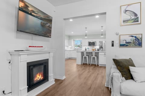 A modern living room with a fireplace, television, and an open kitchen.