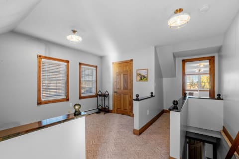 Home hallway with gray walls, wooden trim, and lighting fixtures.