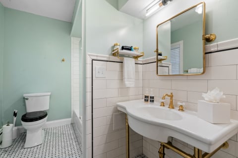 Modern bathroom with mint green walls, white sink, and black and white tiled floor.