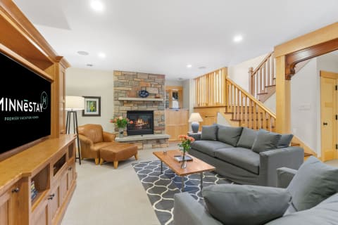 A cozy living room with a stone fireplace and grey sofas.