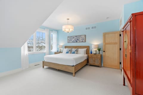 A serene bedroom featuring blue walls, a wooden bed, and stylish decor.