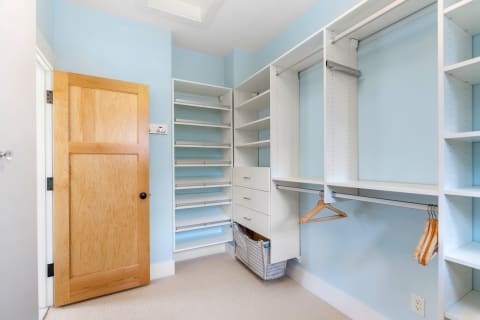 Interior of a minimalist closet with blue walls and organized storage.