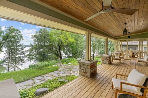 Lakeside porch with seating, stone pathway, and trees in the background.