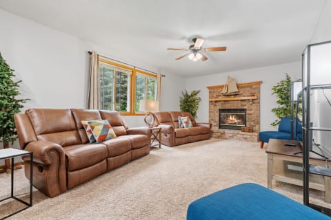 Cozy living room with leather recliners, a brick fireplace, and a blue chair.