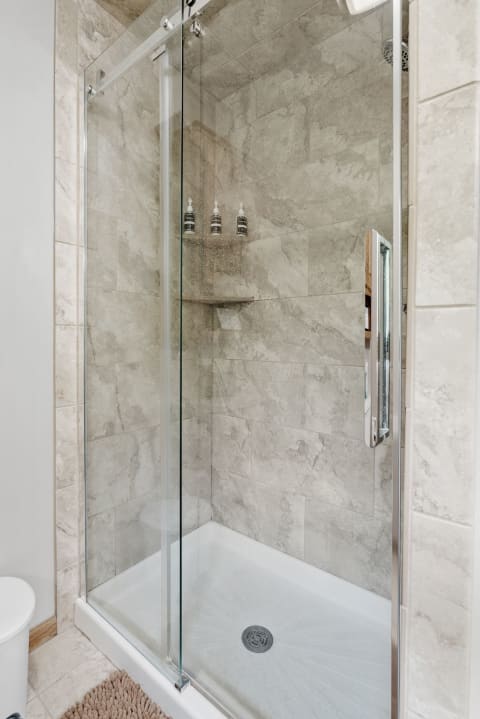 Contemporary shower with glass walls and gray tile background.
