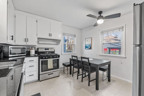 Modern kitchen with black and white decor, featuring a dining area and windows.