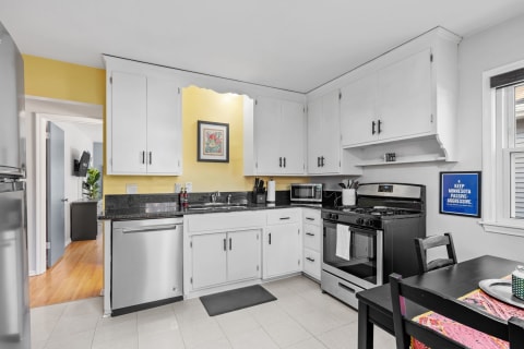 A warm and inviting kitchen featuring white cabinets, black granite countertops, and yellow walls.