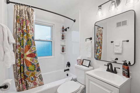 Modern bathroom with colorful floral shower curtain and sleek white vanity.