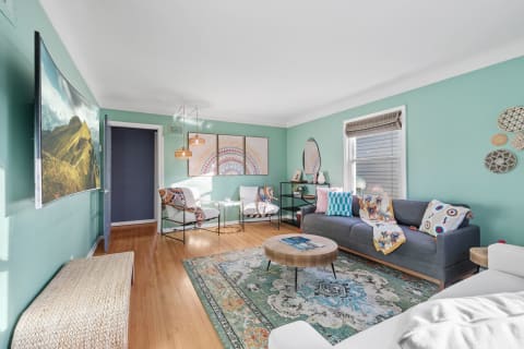 Bright living room with turquoise walls, gray couch, and colorful decor elements.
