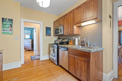A well-designed kitchen featuring dark wood cabinetry, stainless steel appliances, and a vibrant artwork on the wall.