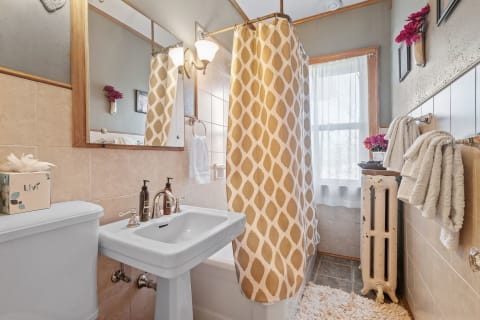 Cozy bathroom with a vintage vibe and modern fixtures, showcasing a sink, shower curtain, and decorative elements.