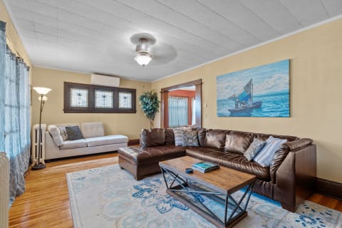 Cozy living room with brown leather couch, coffee table, and sailing artwork.