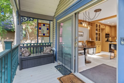 A welcoming porch with a dark bench, stained glass window, and a view into a modern kitchen.
