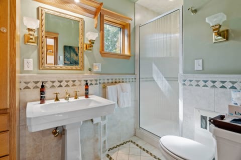 A well-appointed bathroom with a pedestal sink, ornate mirror, and shower cubicle.