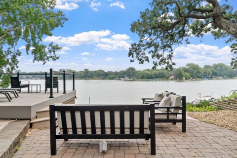 Outdoor seating area by a lake with modern furniture and a clear sky.