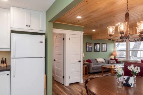 Open-plan living and dining area with modern decor, featuring a gray sofa, dining table, and white refrigerator.