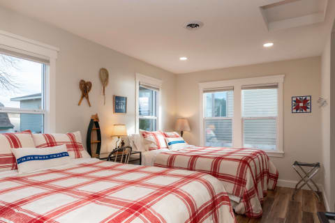 A cozy bedroom with two beds, red and white checkered bedding, and rustic decor items.
