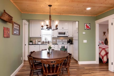 Interior view of a kitchen and dining area with a round table, rustic decor, and modern appliances.