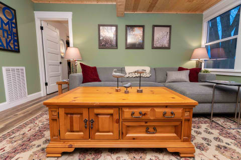 A cozy living room with a wooden coffee table, gray sectional sofa, and framed nature photographs.