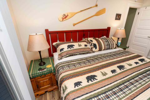 Interior view of a rustic-themed bedroom featuring bear-patterned bedding and a canoe paddle on the wall.