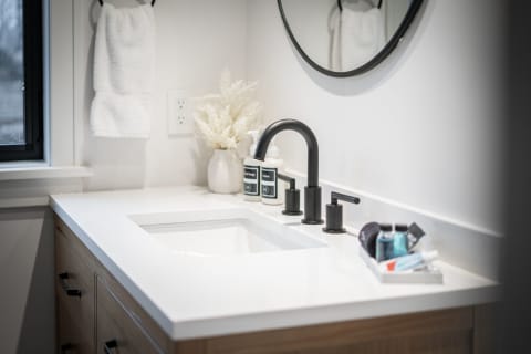 Modern bathroom sink with black faucet, white countertop, and decorative elements.