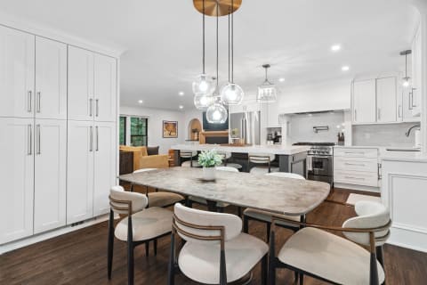 Modern kitchen with dining area, featuring light fixtures and sleek cabinetry.
