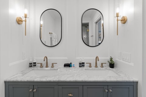 A contemporary bathroom vanity with gray cabinets, marble countertop, and rose gold fixtures.