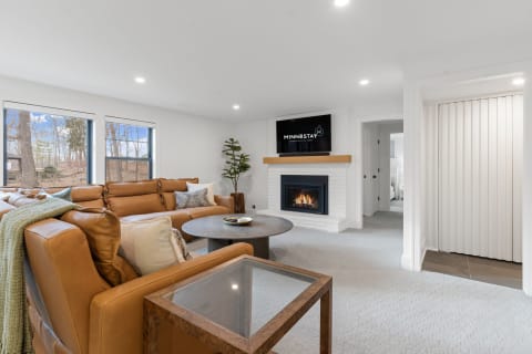Cozy living room featuring a brown leather sectional, a fireplace, and modern decor.