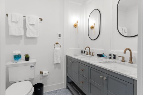 Modern bathroom with a white and grey color scheme, featuring a marble countertop and gold fixtures.