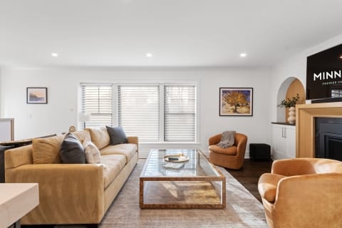 Modern living room featuring a beige sofa, glass coffee table, and caramel armchairs.