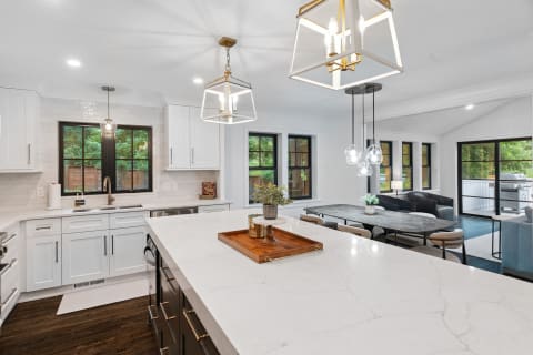 Modern kitchen with white cabinetry and a dining area featuring a dark wood table and plush chairs.