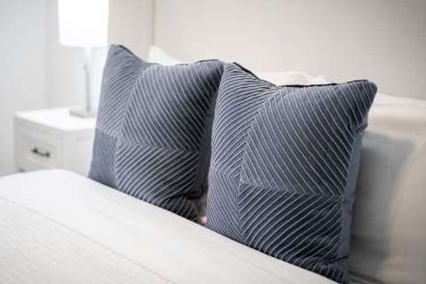 Two decorative navy blue pillows with textured patterns on a bed.