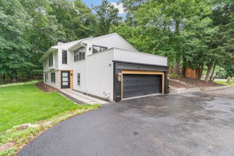 Contemporary house with white siding and large windows surrounded by trees.
