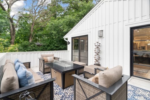 Outdoor balcony featuring comfortable furniture and lush green trees in the background.