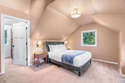 Cozy attic bedroom featuring sloped ceilings, a gray bed, and a natural view.