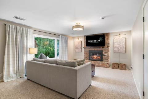Inviting living room featuring a gray sectional sofa, a brick fireplace, and a flat-screen TV.