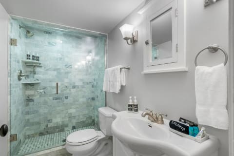Modern bathroom with glass shower, marble tiles, and white sink.