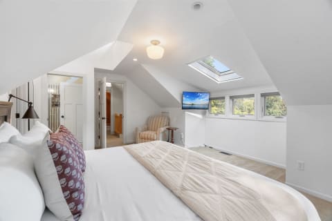 An attic bedroom featuring a bed, armchair, and skylight.