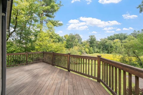 Wooden deck with a lush green backdrop and blue sky.