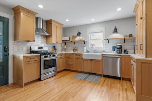 A contemporary kitchen featuring warm wood cabinetry and modern stainless steel appliances.