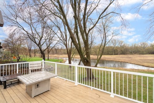 A peaceful river view from a wooden deck surrounded by bare trees.
