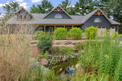 A charming blue house surrounded by a lush garden and pond.
