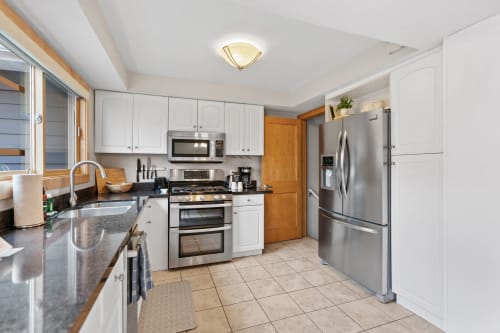 A contemporary kitchen with white cabinets and stainless steel appliances.