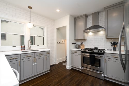 A modern kitchen featuring gray cabinets and stainless steel appliances.