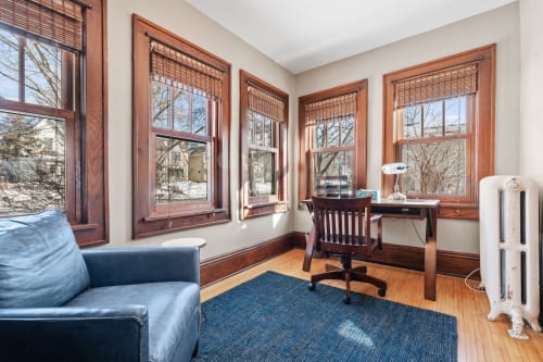 A bright and cozy workspace featuring large windows and vintage charm.