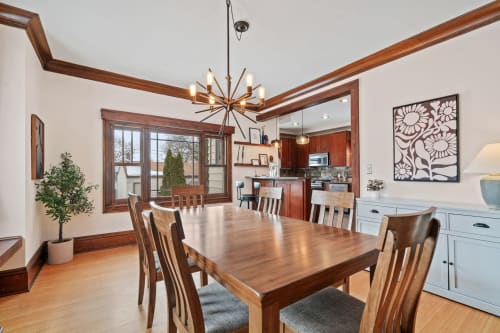 A modern dining room with a unique chandelier and an open kitchen view.